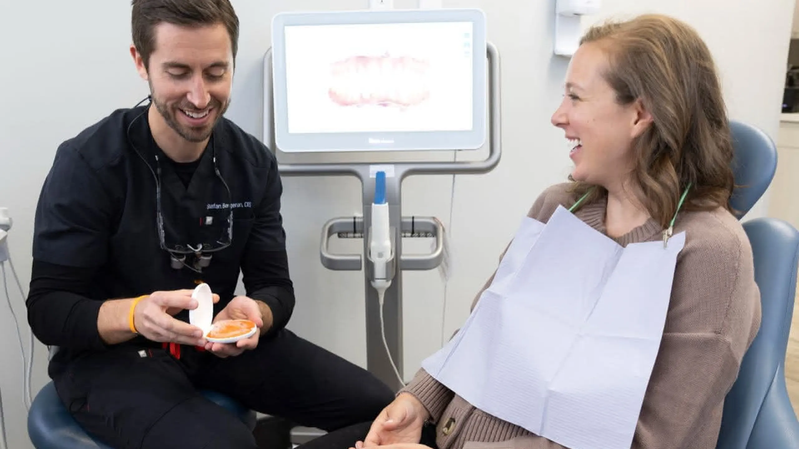 A dentist holding a mirror in front of a patient in a dental chair