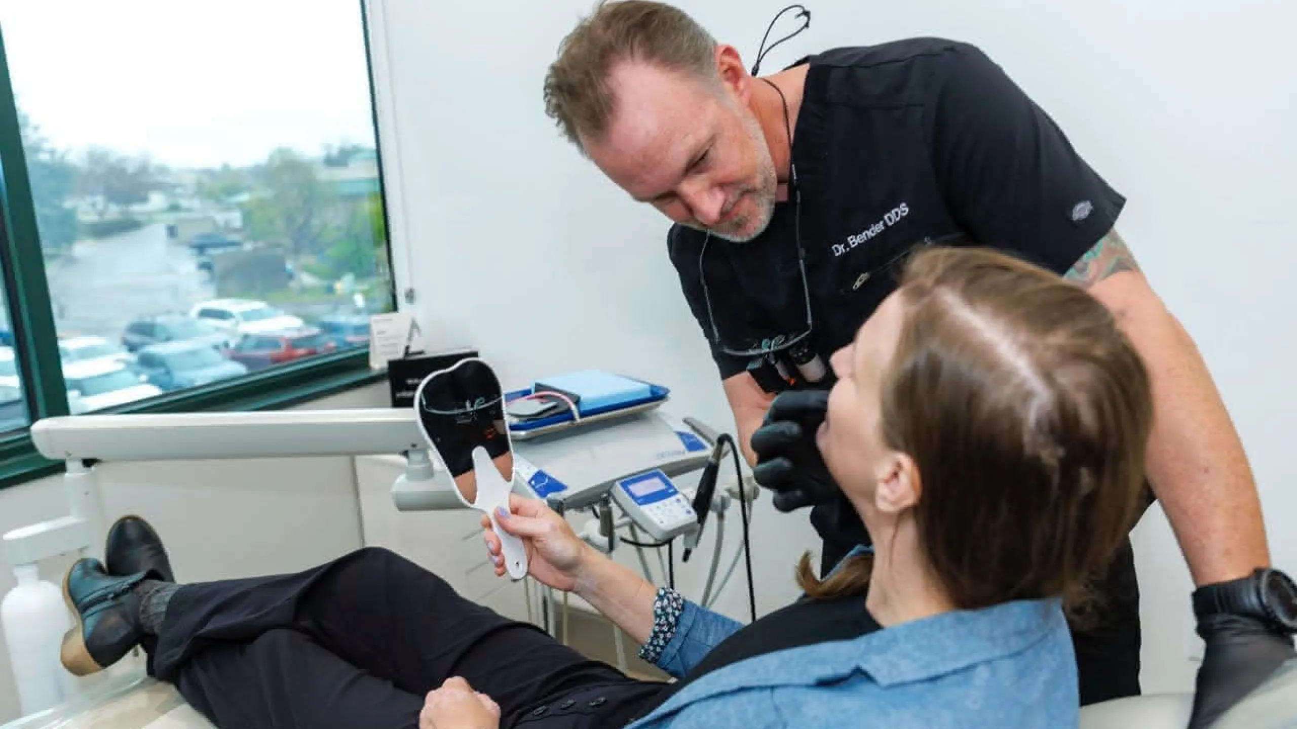 Dr. Bender examining a patient holding a hand mirror