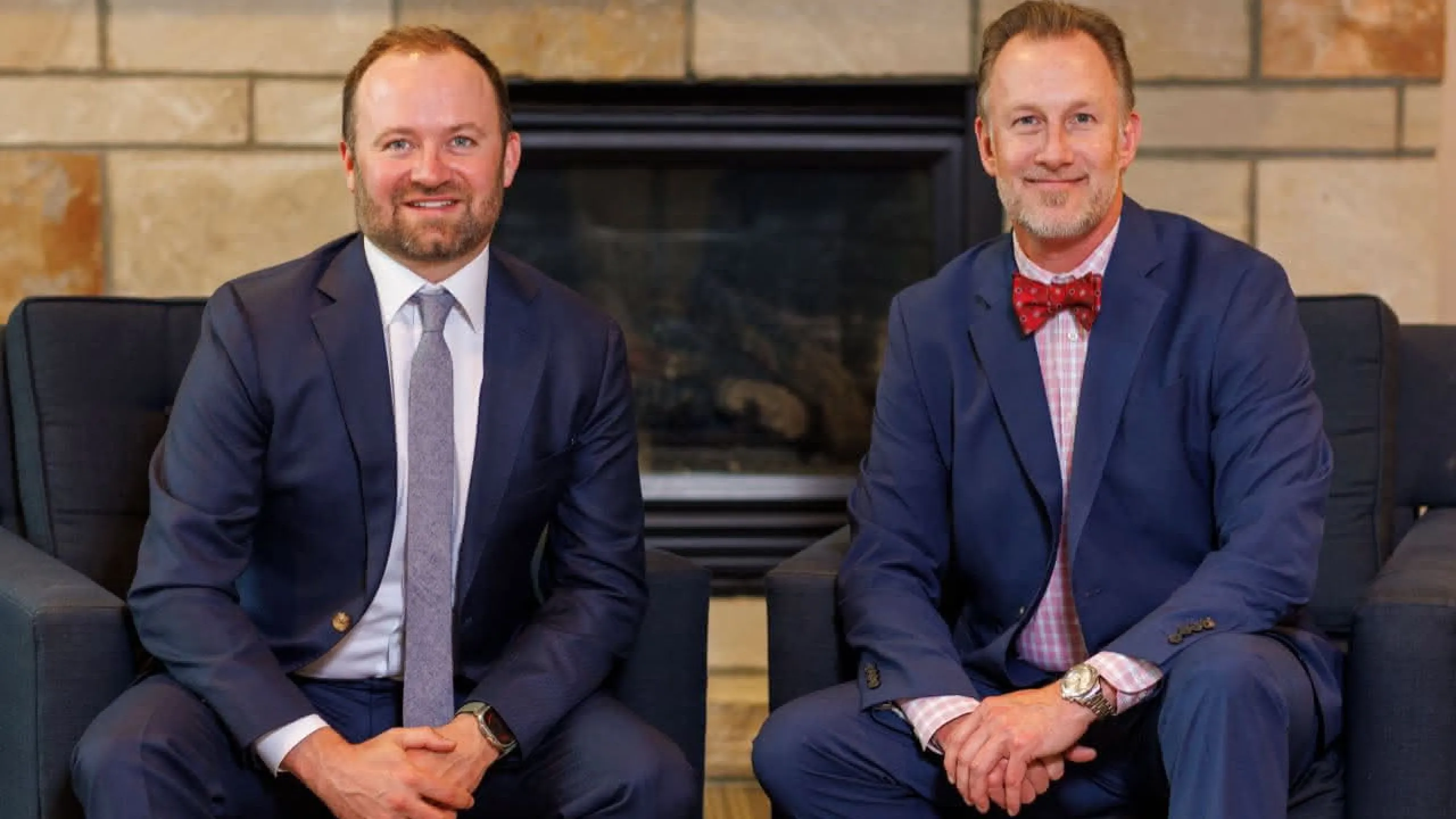 Two doctors in suits in front of a fireplace