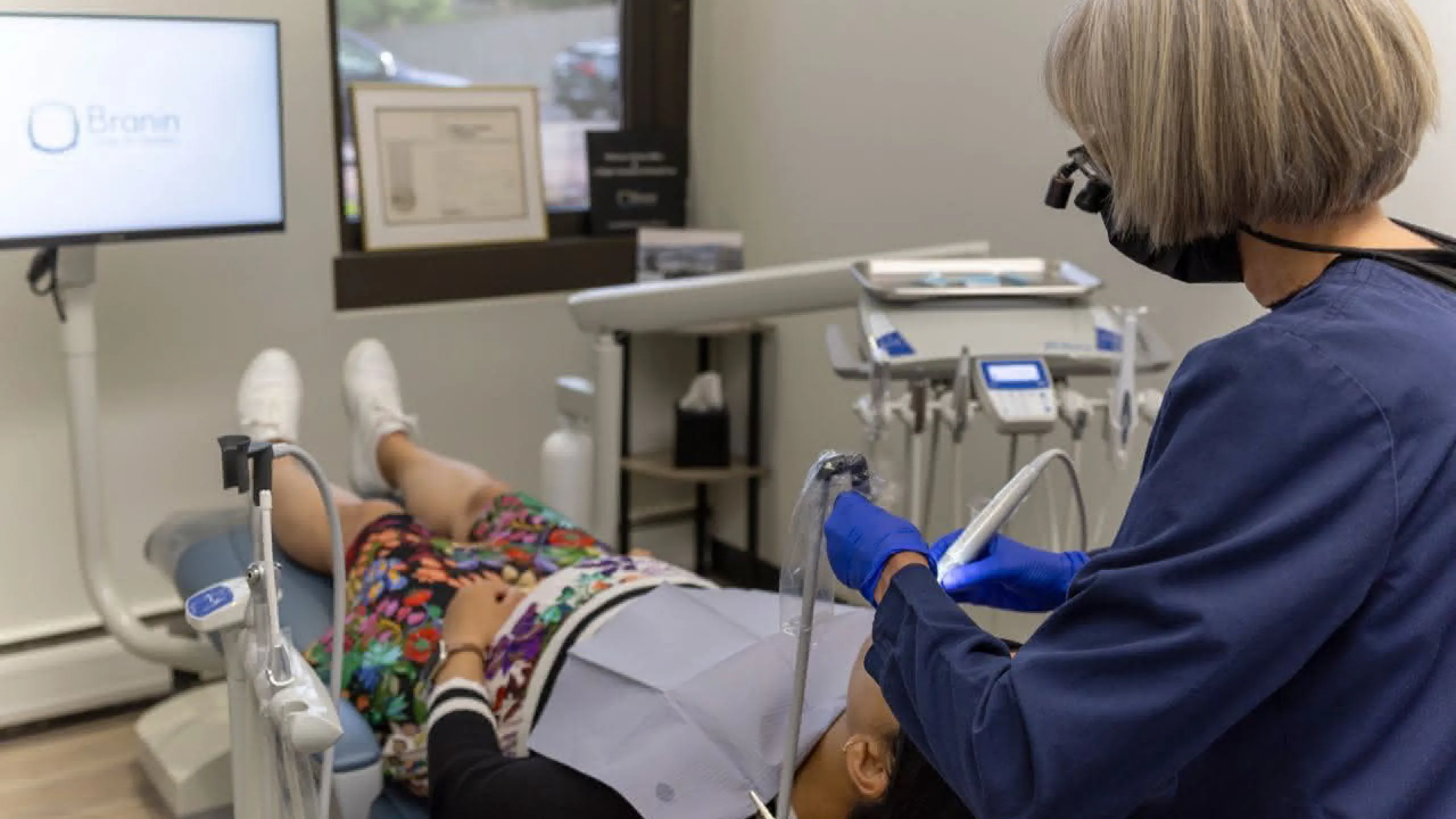 A staff member cleaning the teeth of a patient