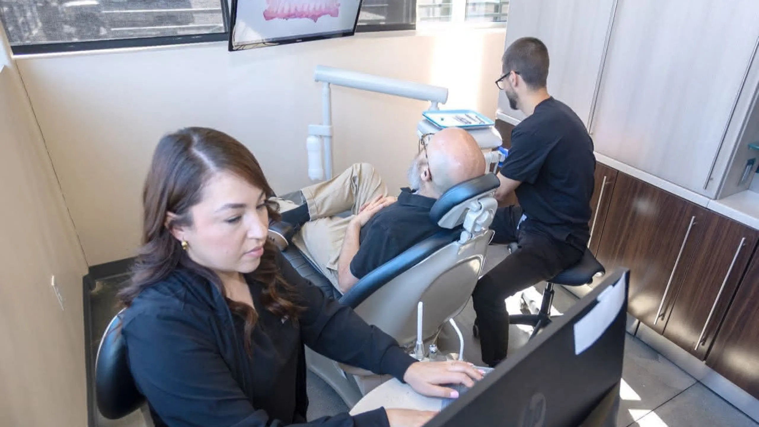 A hygienist and doctor working on a patient in a dental chair