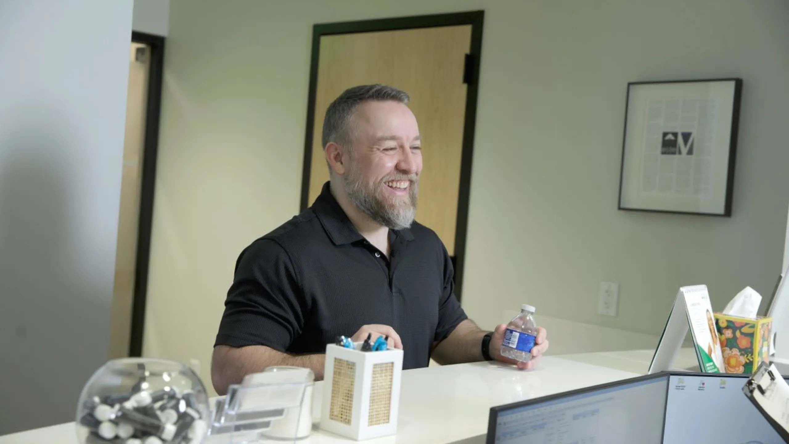 A man holds a bottle of water at the front desk
