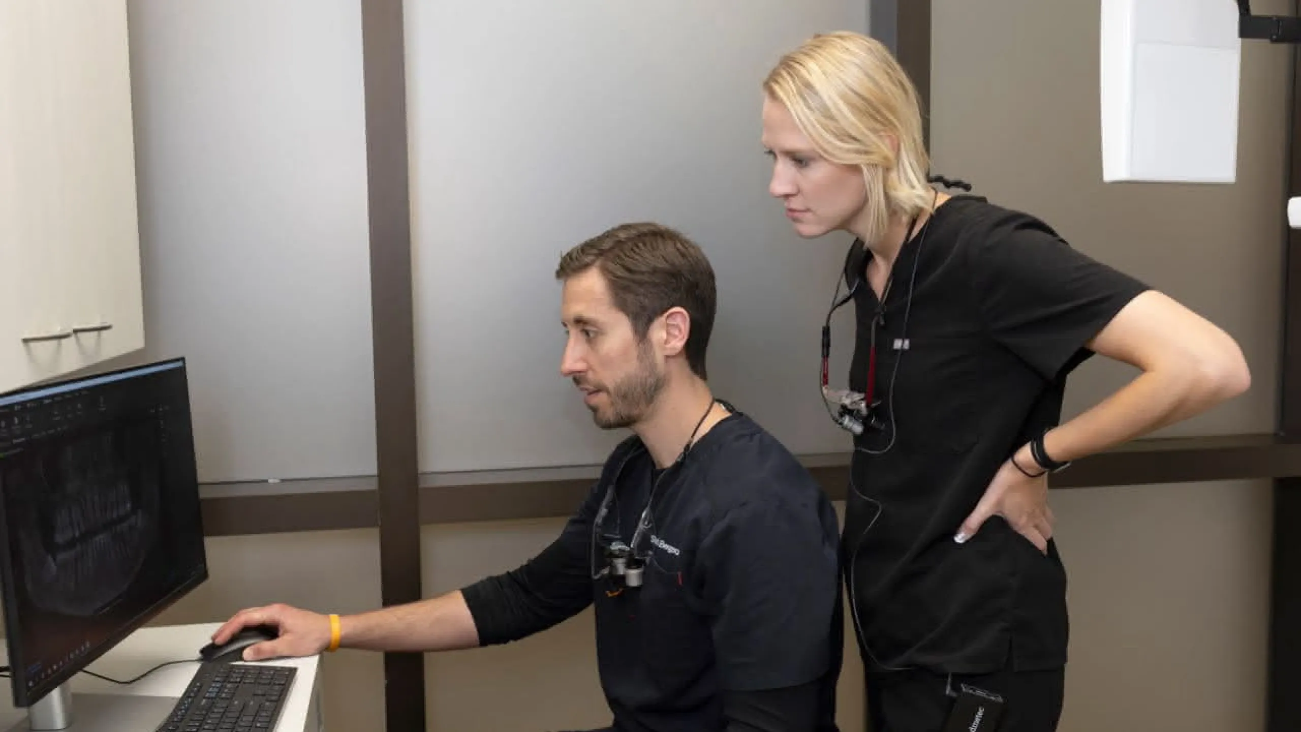 Staff stands behind doctor at computer reviewing patients X-ray