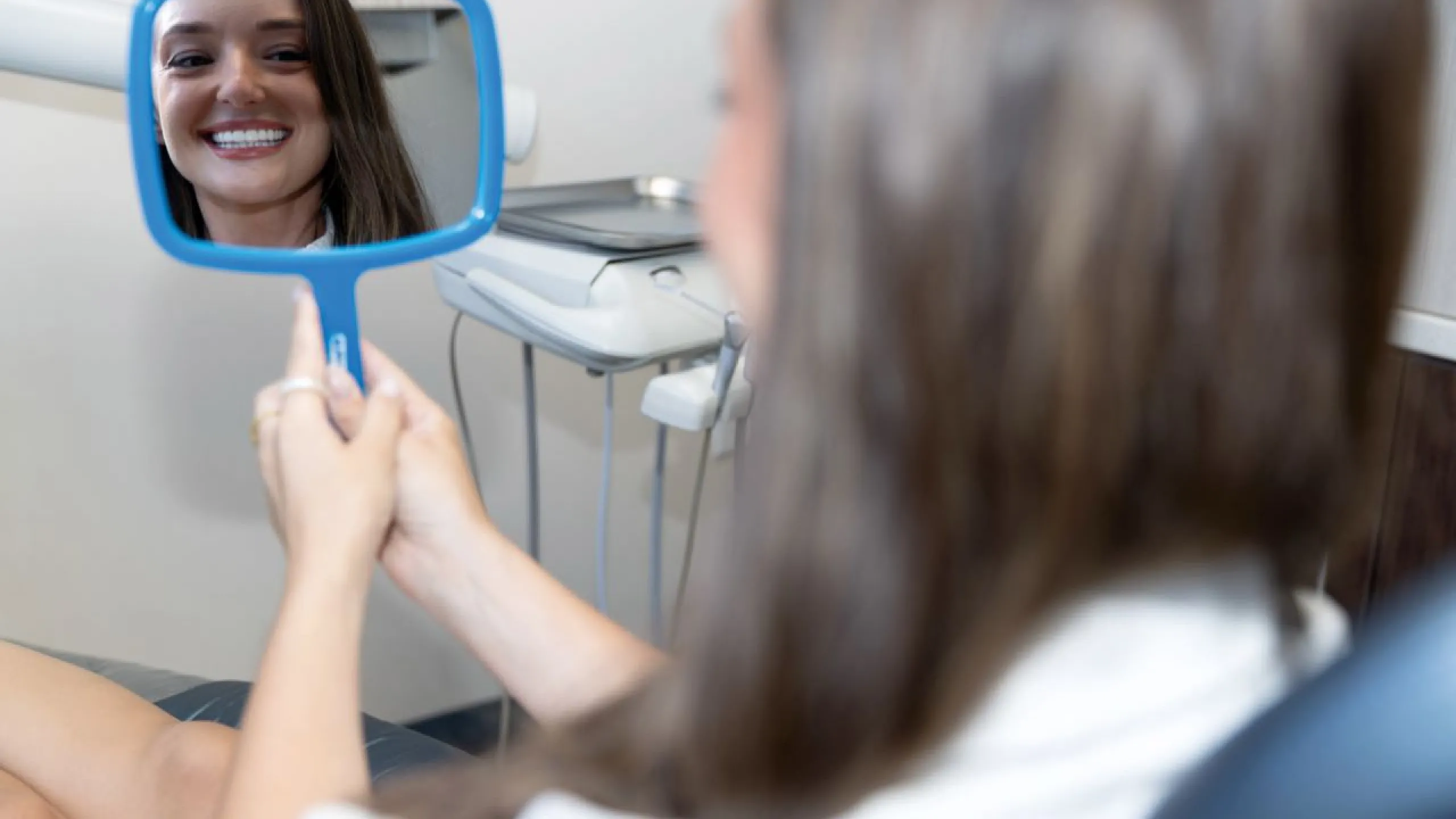 Patient holding blue mirror smiling