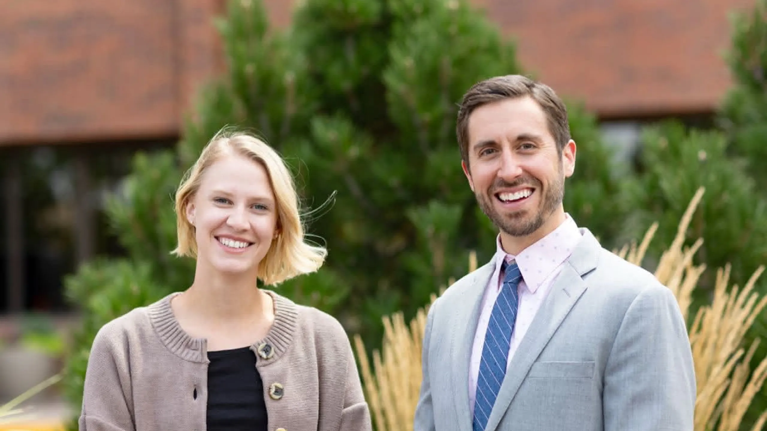 Two doctors standing in front of prairie grass smiling