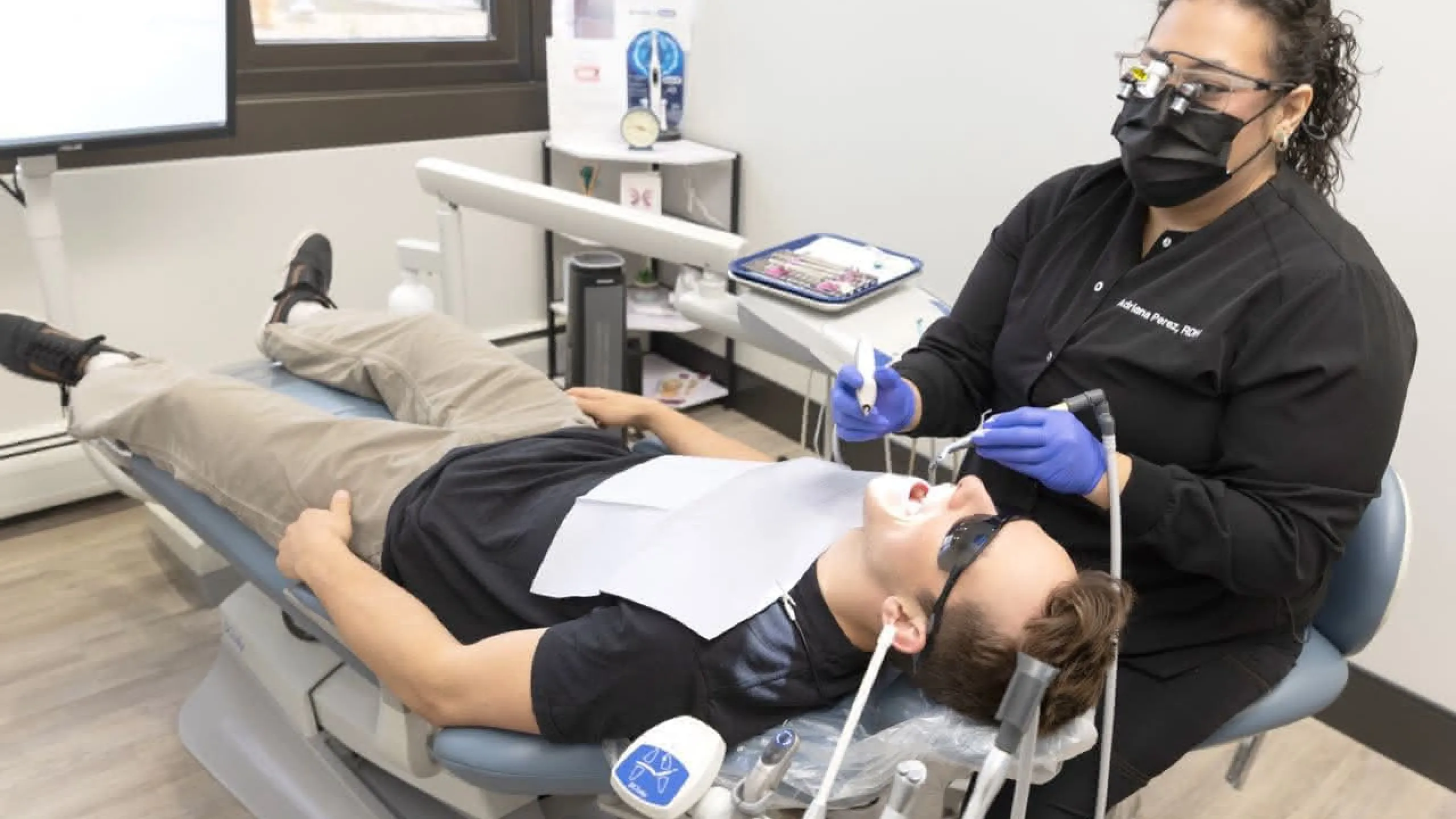 A patient in a dental chair wearing eye protection
