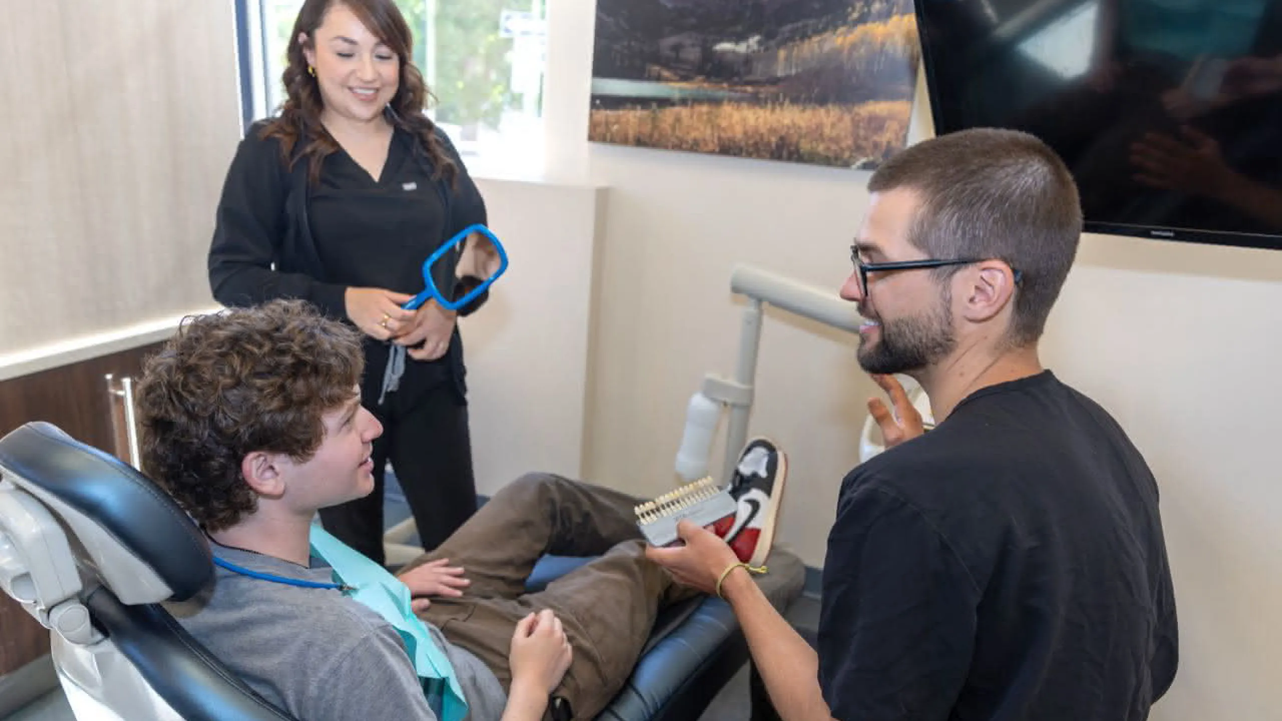 A doctor showing a patient a tooth color scale
