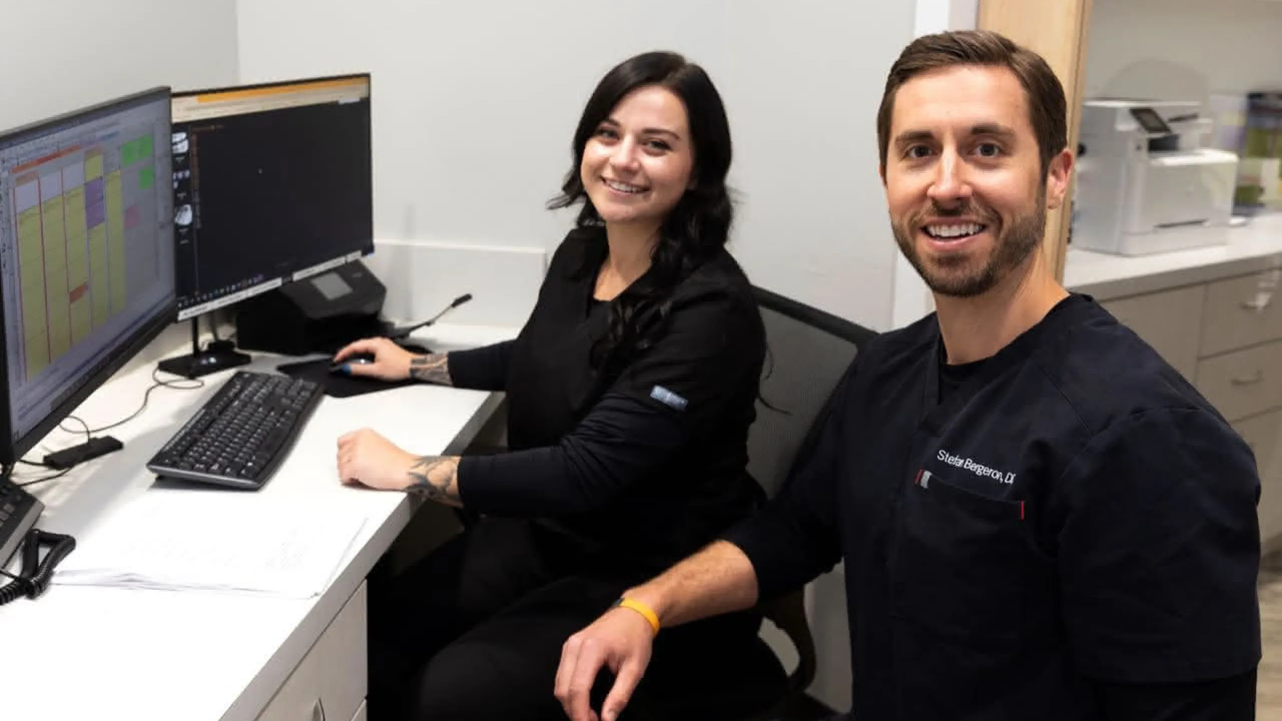 A dental assistant at a computer with a dentist off to the side
