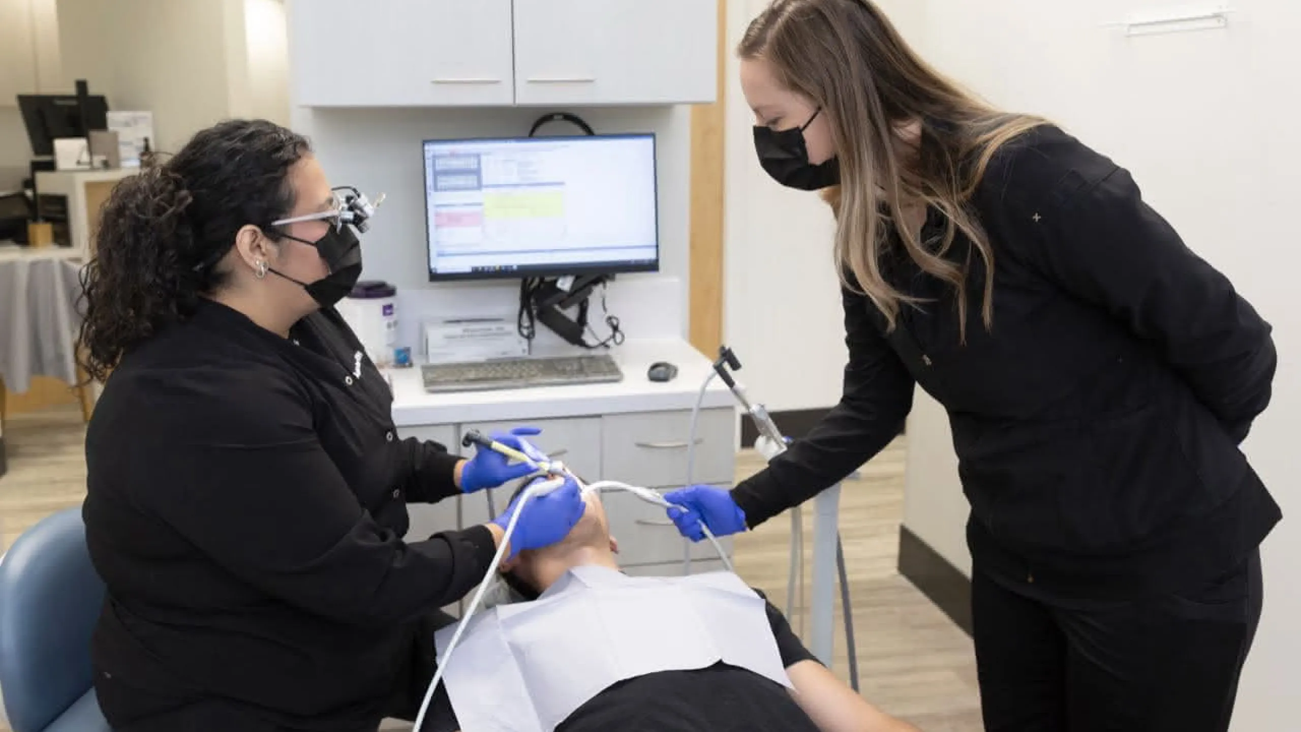 A hygienist and a dental assistant working on a patient 