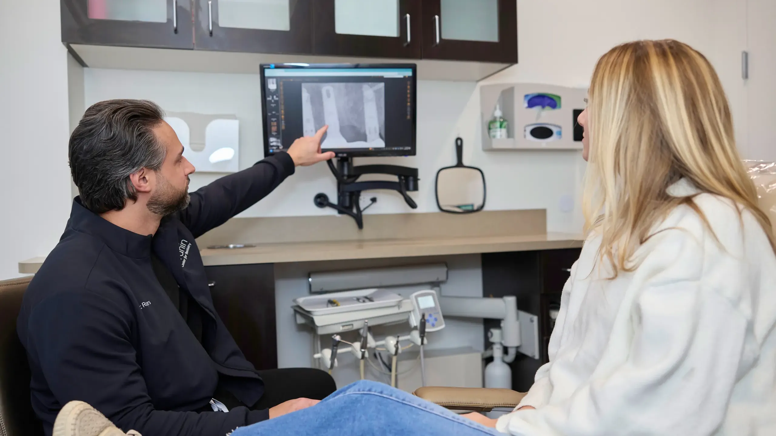A doctor pointing at an x-ray on a monitor
