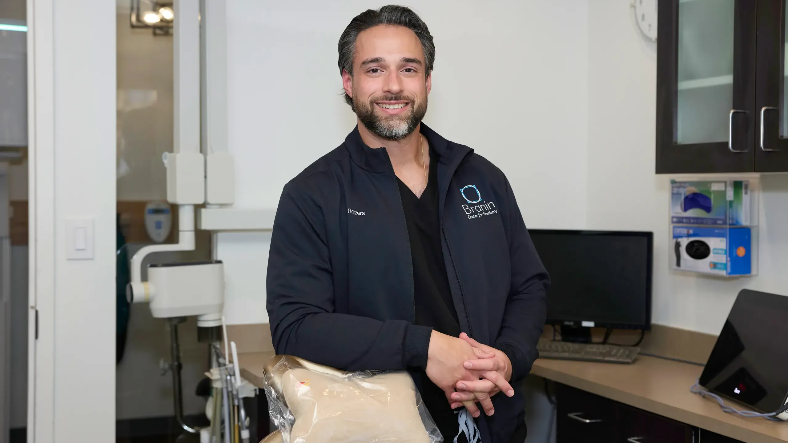 Dr. Rogers leaning on a tan dentist chair