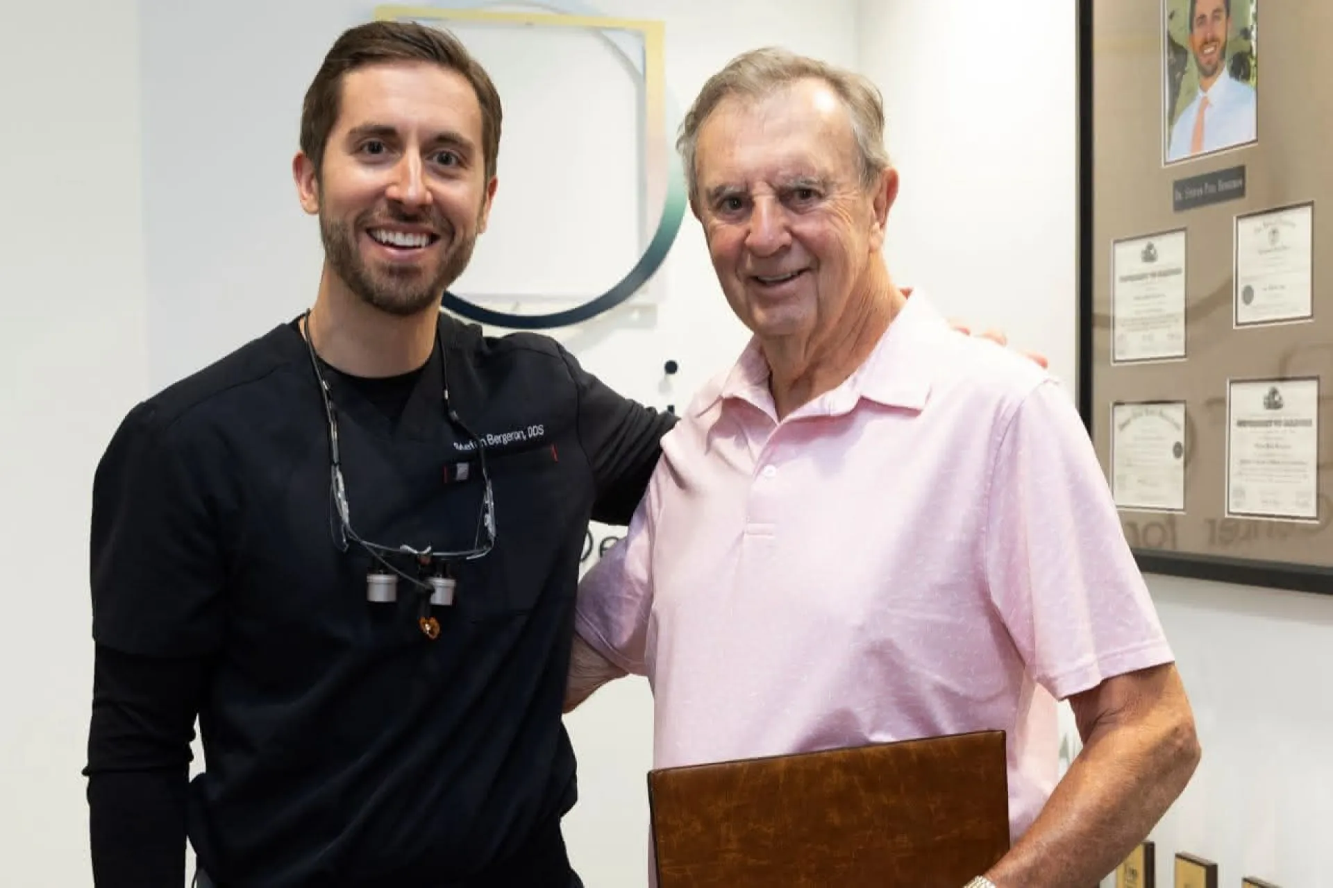 A dentist with a patient in a pink shirt holding a folder