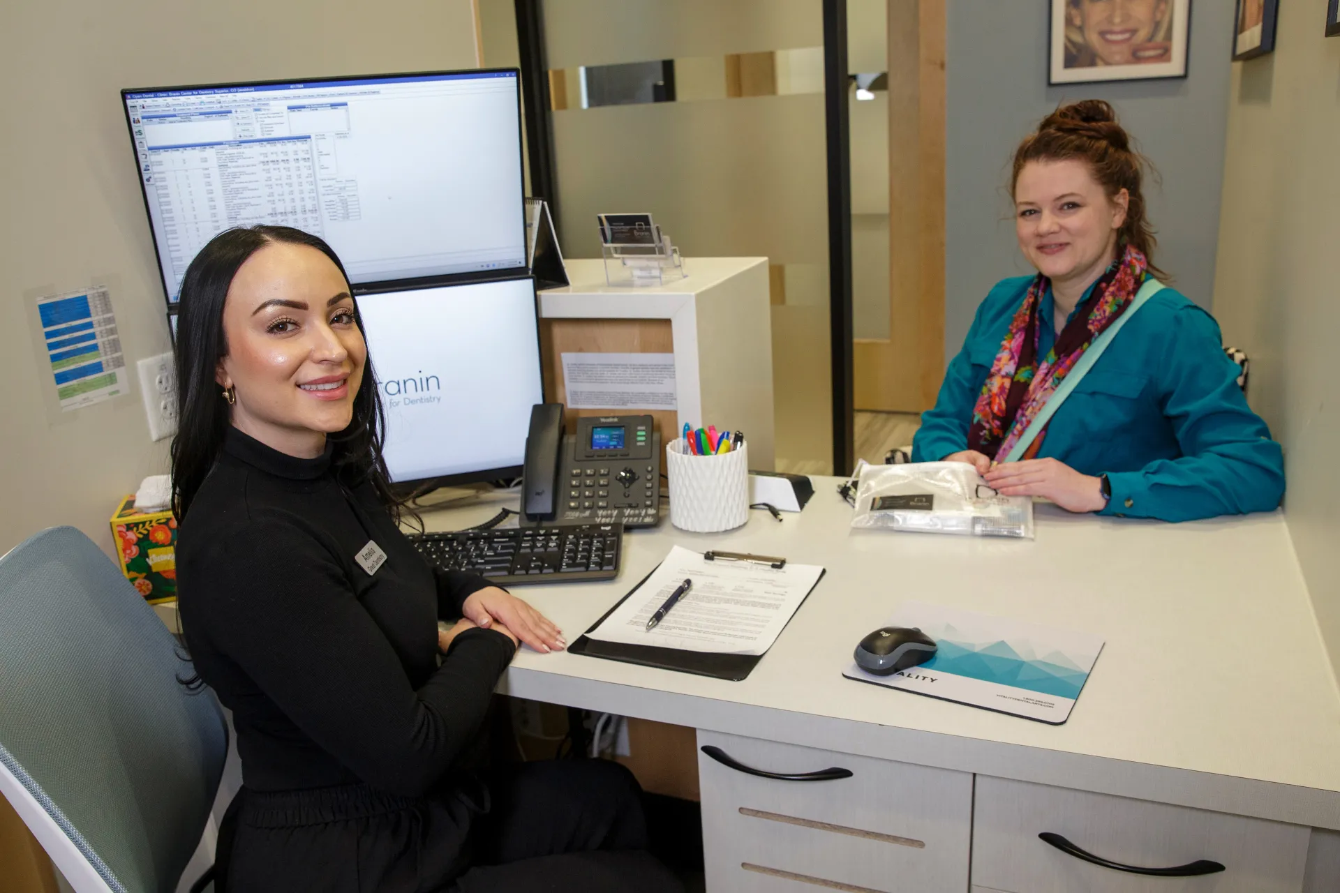 An employee helping a patient at a desk and smiling