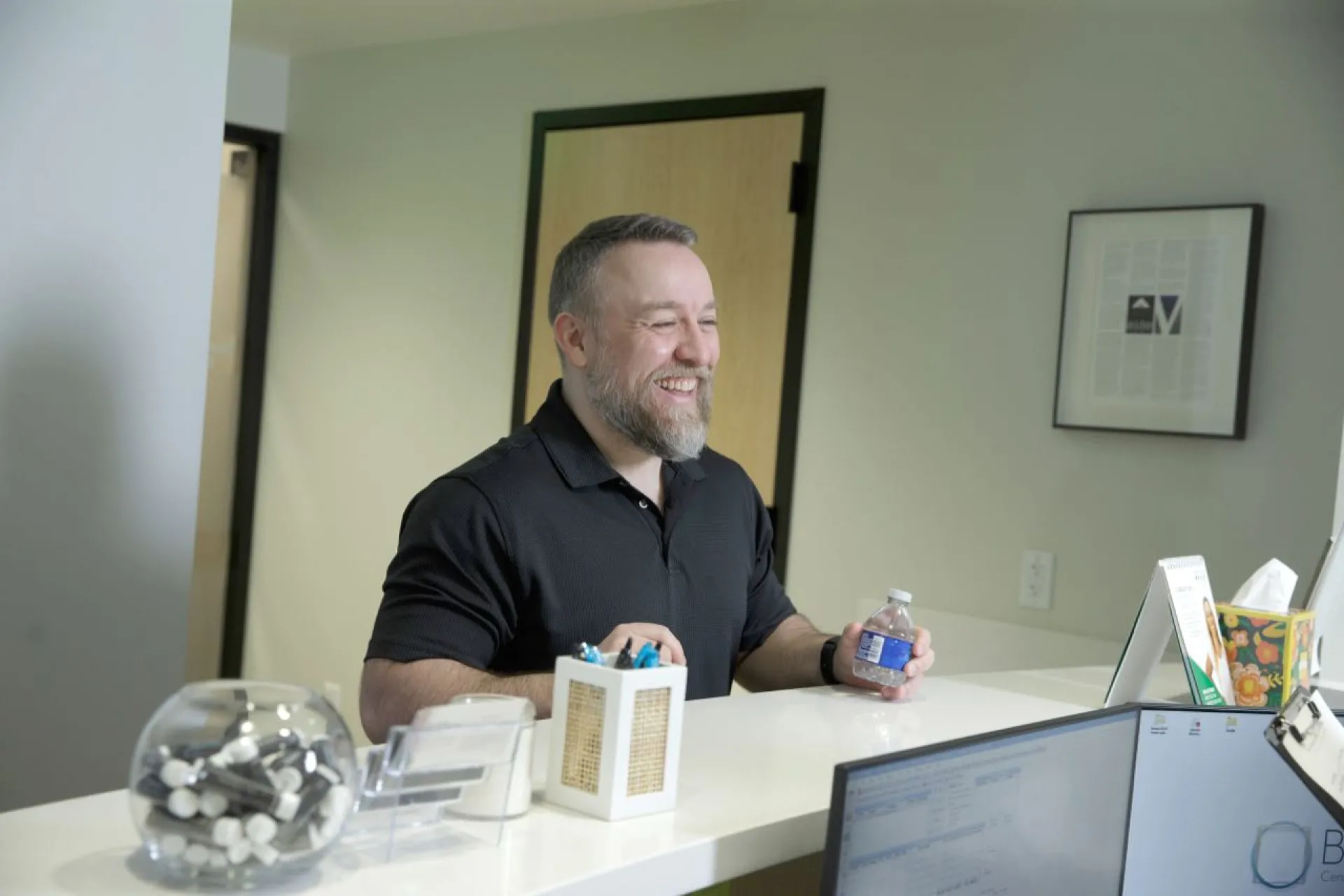 A man holds a bottle of water at the front desk