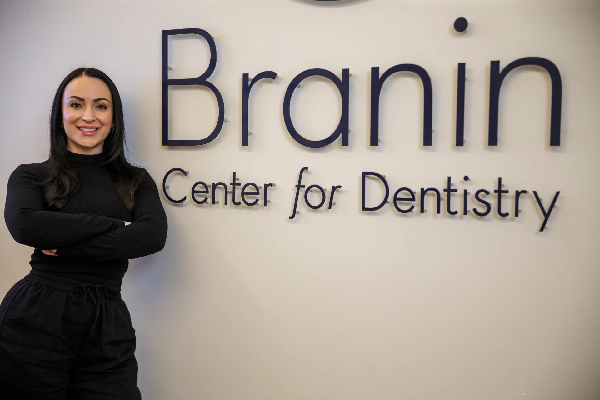 Branin Employee smiling in front of Branin Center for Dentistry sign.
