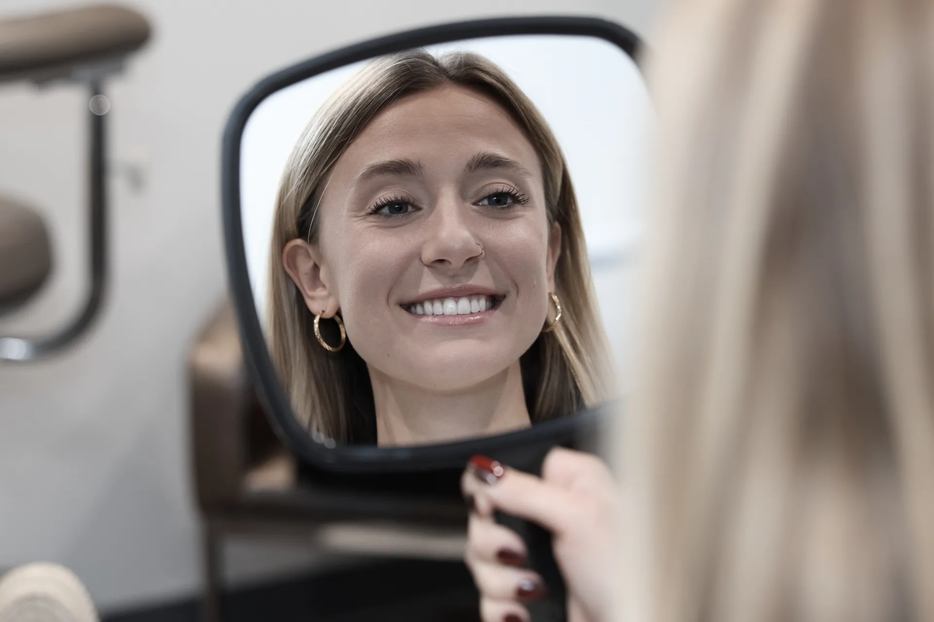 A patient smiling in a mirror with a beautiful smile.