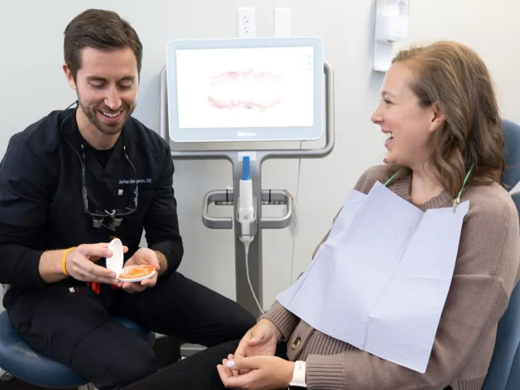 A dentist holding a mirror in front of a patient in a dental chair
