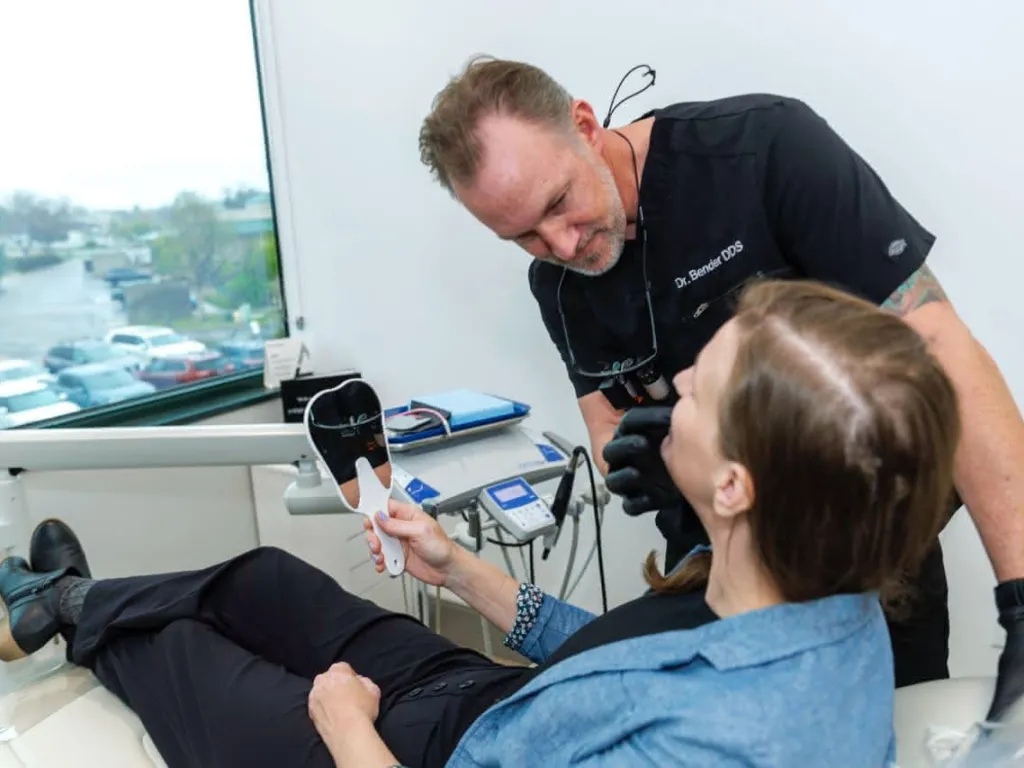 Dr. Bender examining a patient holding a hand mirror