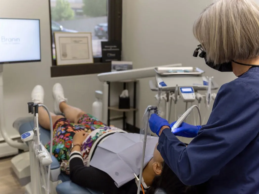 A staff member cleaning the teeth of a patient