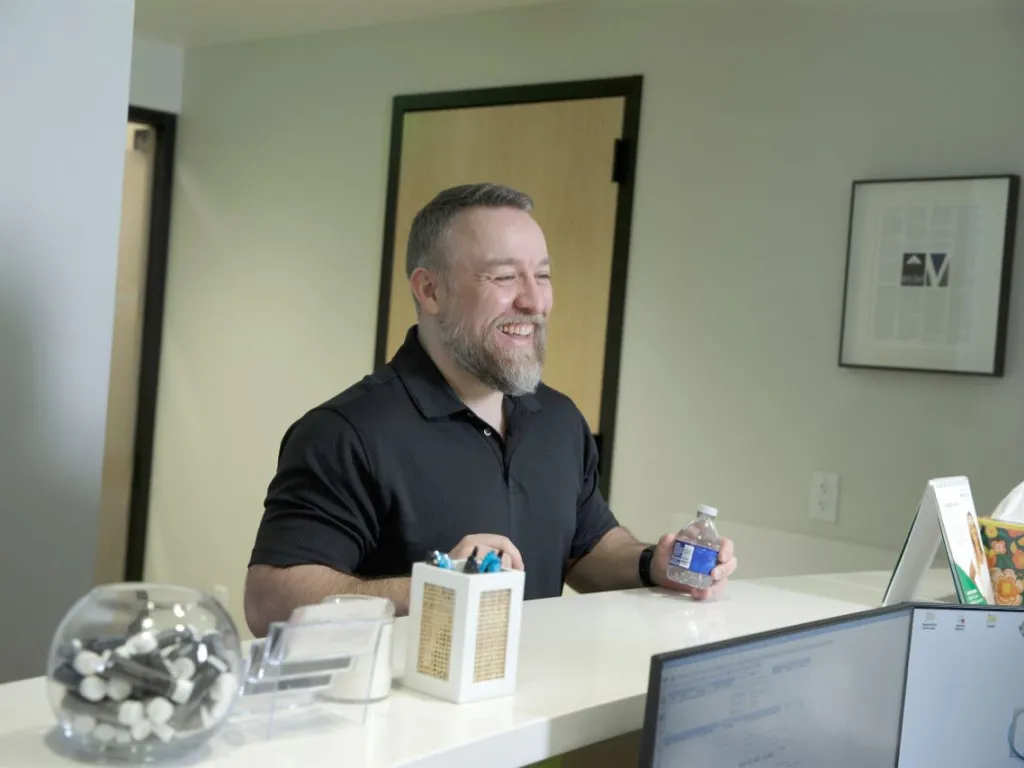 A man holds a bottle of water at the front desk