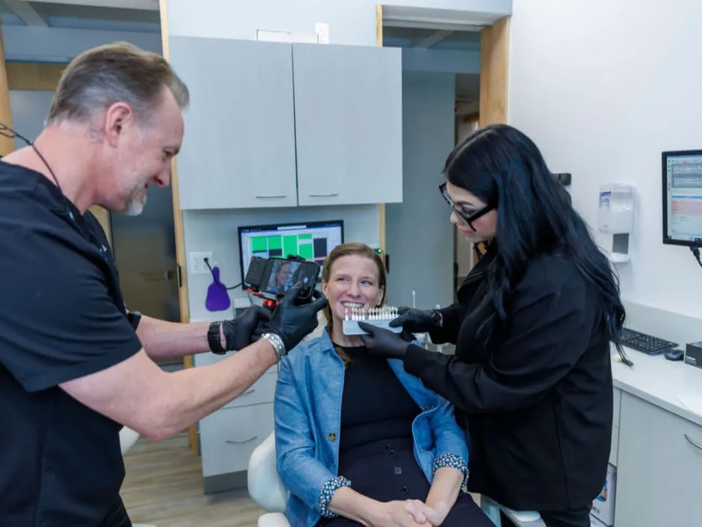 A doctor and assistant showing patient tooth color examples