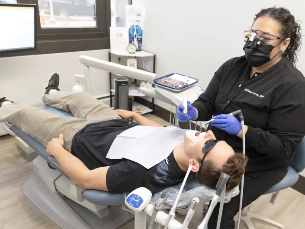 A patient in a dental chair wearing eye protection