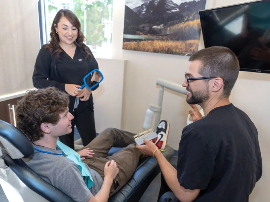 A doctor showing a patient a tooth color scale