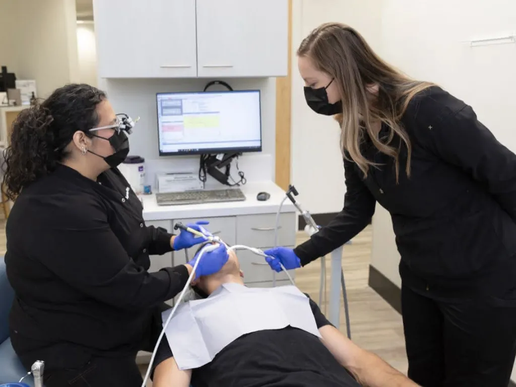 A hygienist and a dental assistant working on a patient 