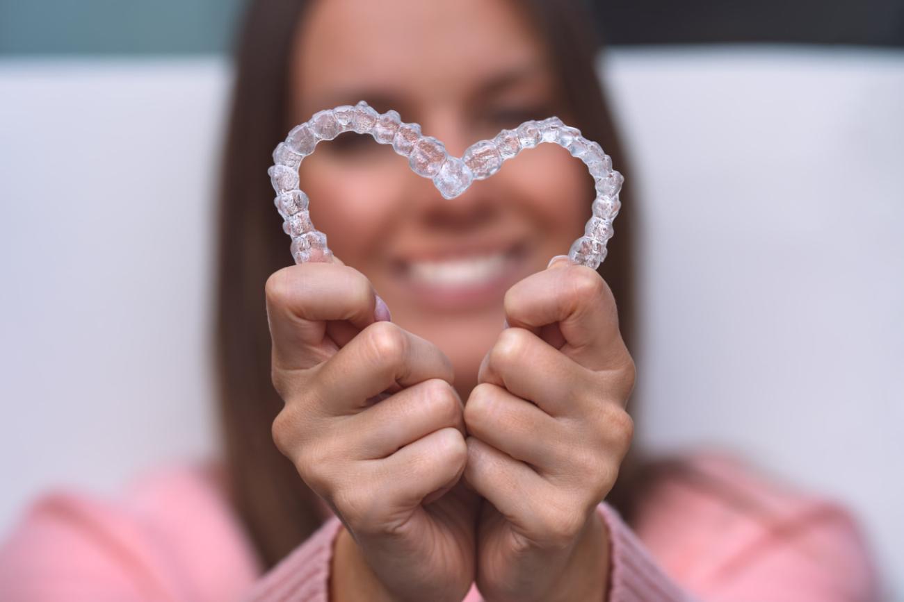 A person holding two teeth aligners in a heart shape