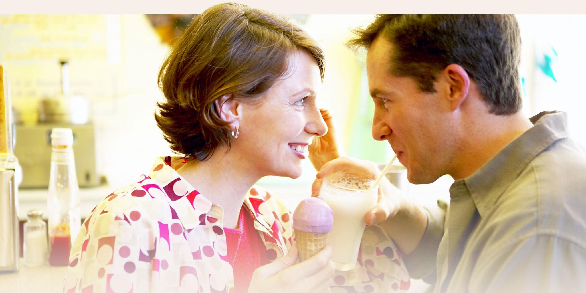 A couple looking at each other while eating ice cream