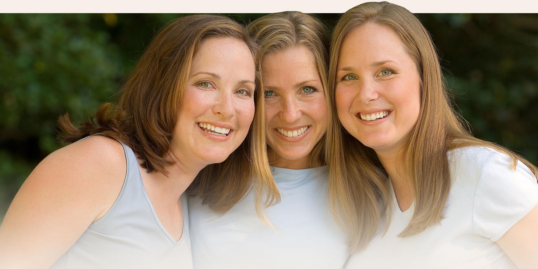 Three women posing and smiling for a group photo