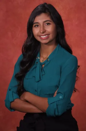 Dr. Karly Vera standing in front of a red backdrop