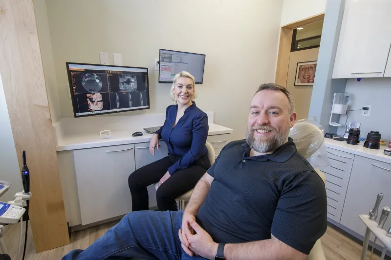 Dr. Sesson and a smiling patient sitting together in the operatory.
