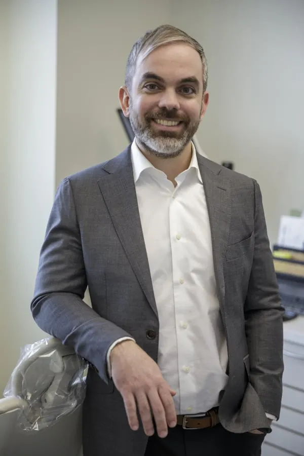 Dr. John Sporidis leaning on a dental chair