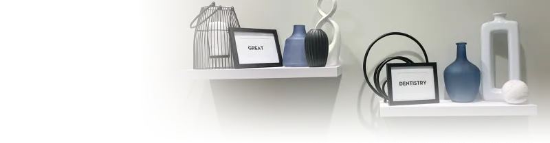 Two small wall shelves holding small vases and two frames. One frame says, "Great" and the other says, "Dentistry".