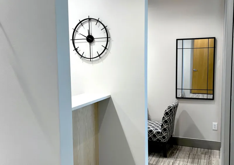 A hallway with art and black and white chair
