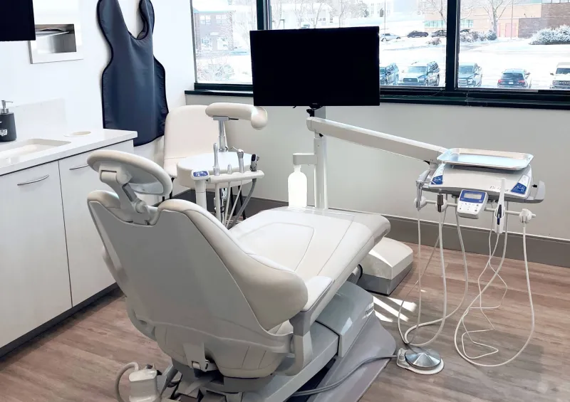A white dentist chair in a dentist exam room with a large window
