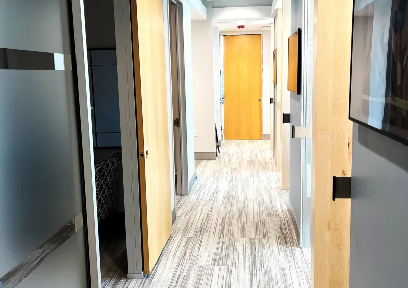 A hallway with light brown wood doors and a hardwood floor