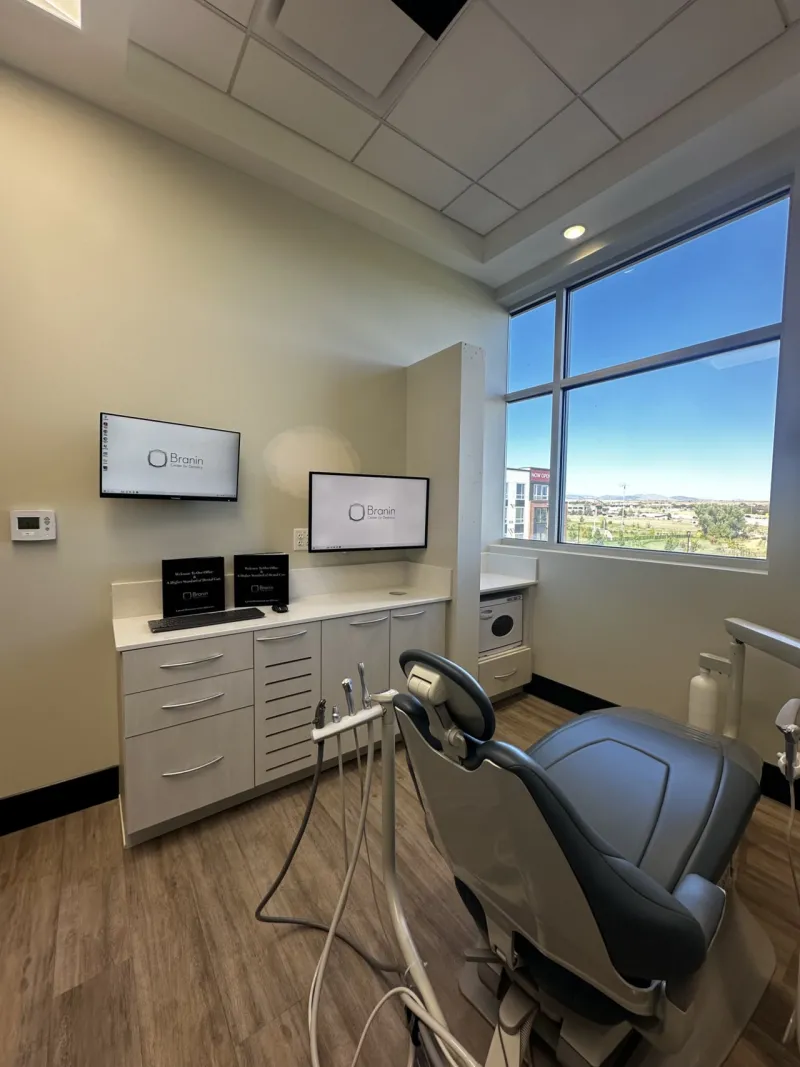 A black dental chair in a room with hardwood floors