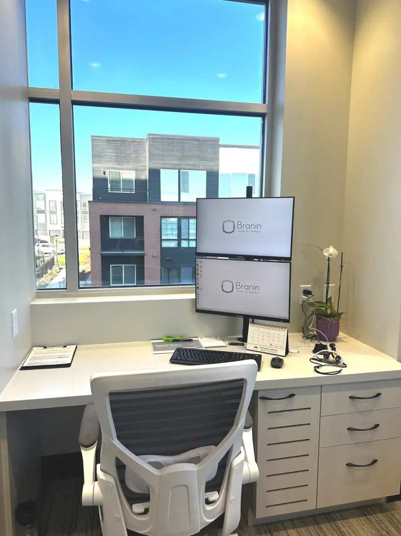 A desk with a monitor and white chair