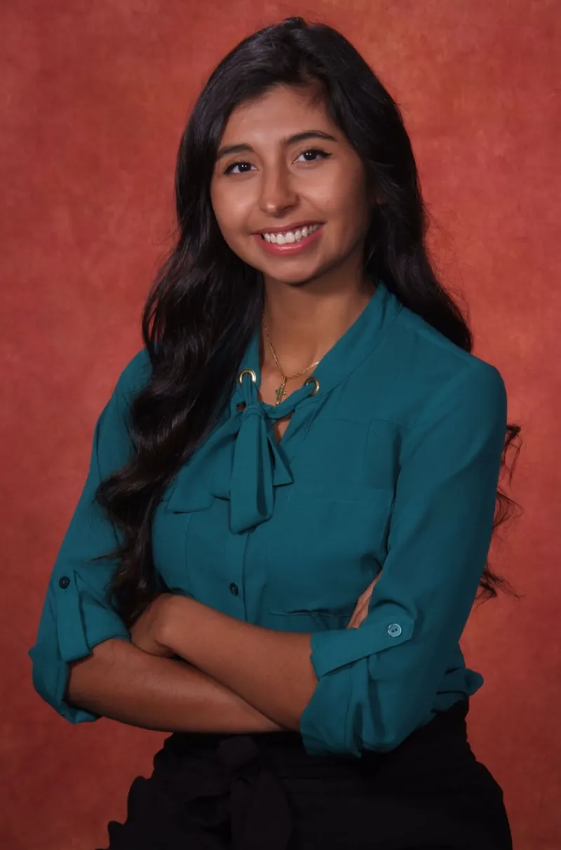 Dr. Karly Vera standing in front of a red backdrop