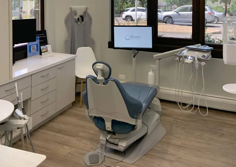 A dentist chair in a neutral color room with wood floor