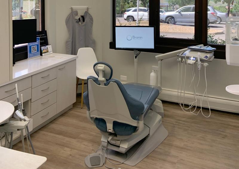 A dentist chair in a neutral color room with wood floor