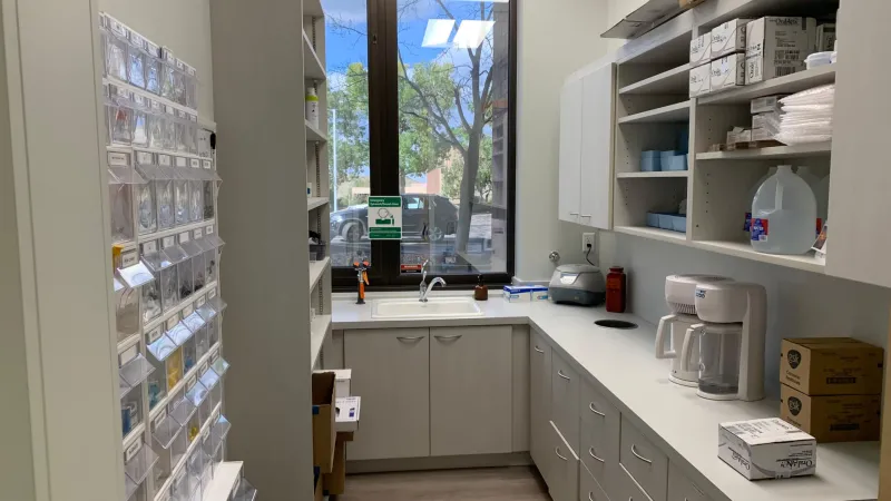 A room with a large window, medical equipment, and drawers