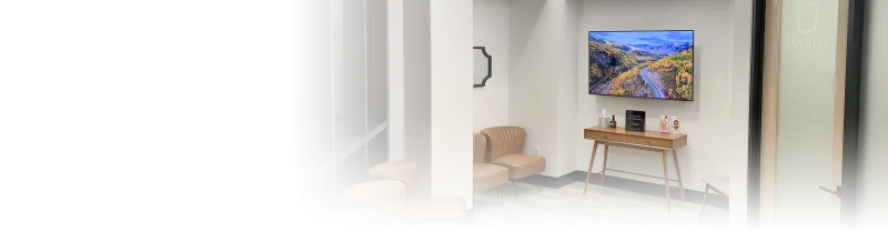 A lobby with a television, chairs, and end-table.