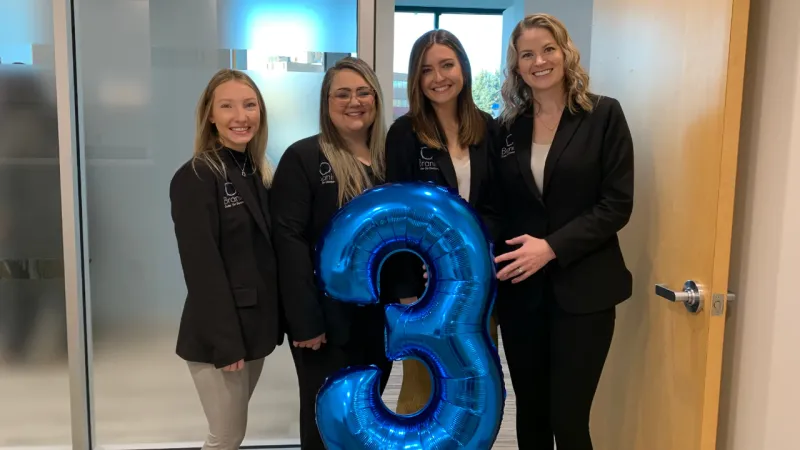 Branin team holding a blue three balloon